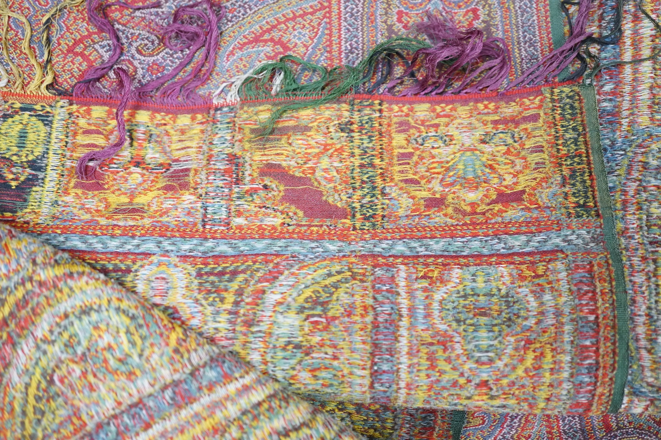 A 19th century woven multi coloured wool and silk Paisley shawl, with large all over paisley tear drop design and brightly coloured fringed borders, 335cm long x 166cm wide